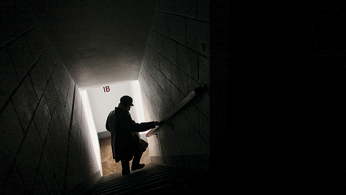 A public housing resident navigates a dark stairwell in a Brooklyn complex that still lacked power two weeks after Hurricane Sandy. New York City Housing Authority buildings damaged by Sandy sat in disrepair for years, while residents also waited for essential services to be restored. Photo by Kirsten Luce/The New York Times.