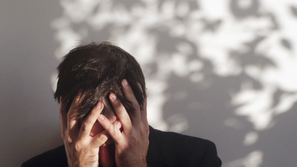 A man covers his head in anguish.