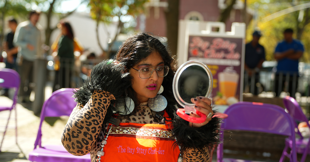 Sabina Sethi Unni with bold jewelry and leopard print looking in a mirror.