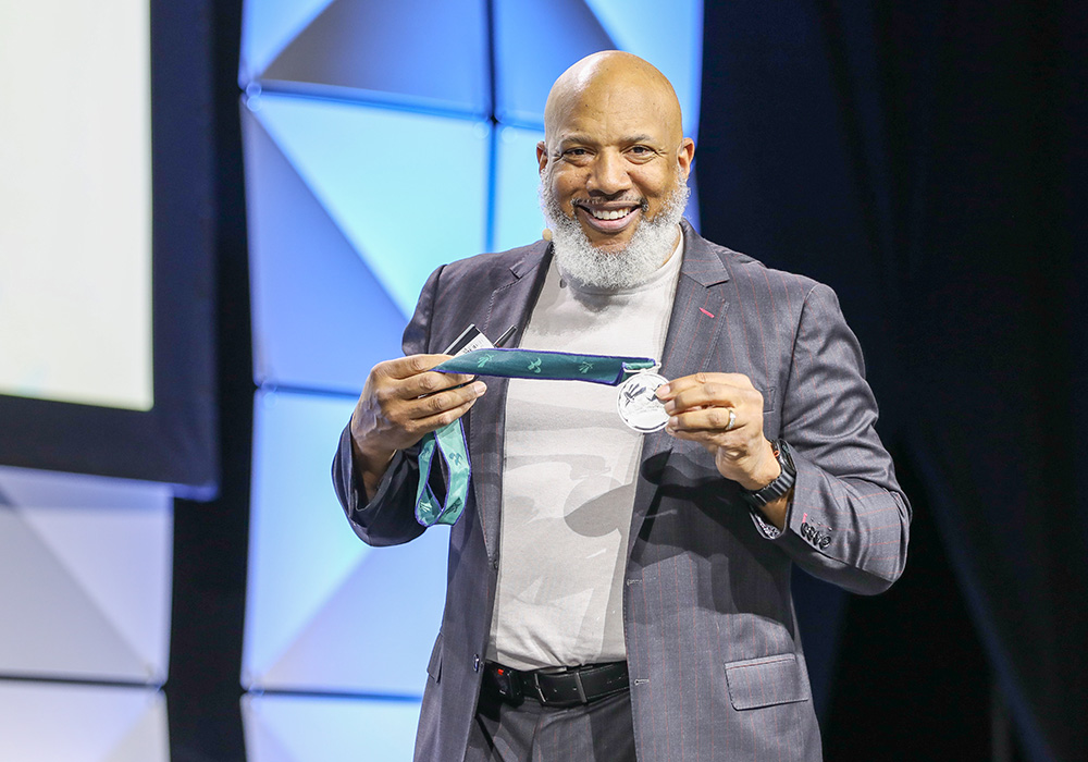 Closing keynote speaker John Register shows the NPC26 crowd the silver medal he earned in the 2000 Paralympic Games.