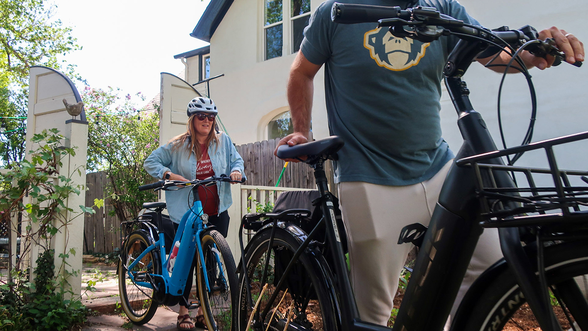 Two Denver residents wheel electric bicycles to the front yard of their home in Denver. The city’s 2022 e-bike rebate program was so popular, it ran out of vouchers. Photo by Nathaniel Minor/CPR News.