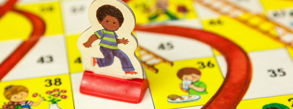 Image of vintage Chutes and Ladders board game and game piece.