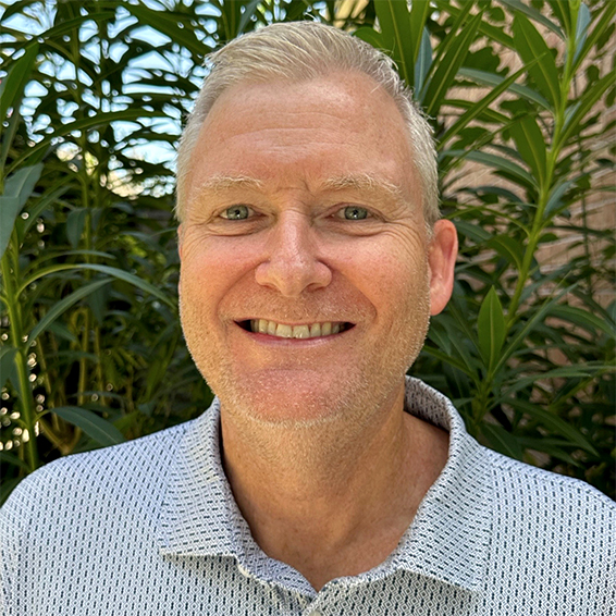 Planning July 2026 Dont Let Words Get in the Way of Successful Resilience Planning image 02 Bret Keast, AICP, a man with gray hair in a gray polo shirt against a green plant backdrop, smiles.