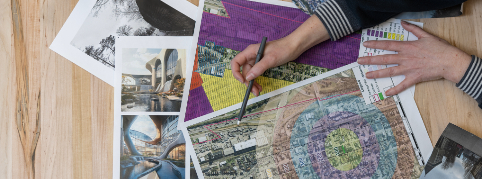 Maps laying across a table with a hand holding a pencil