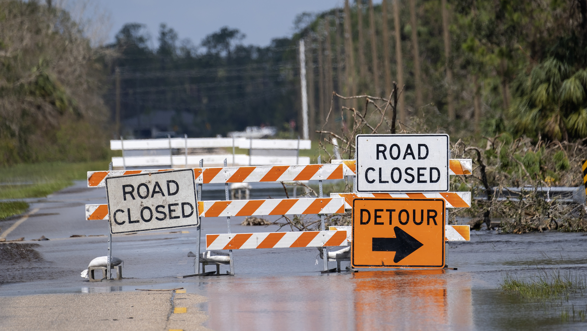 Roud detour signs are places in front of a flooded segment of roadway.