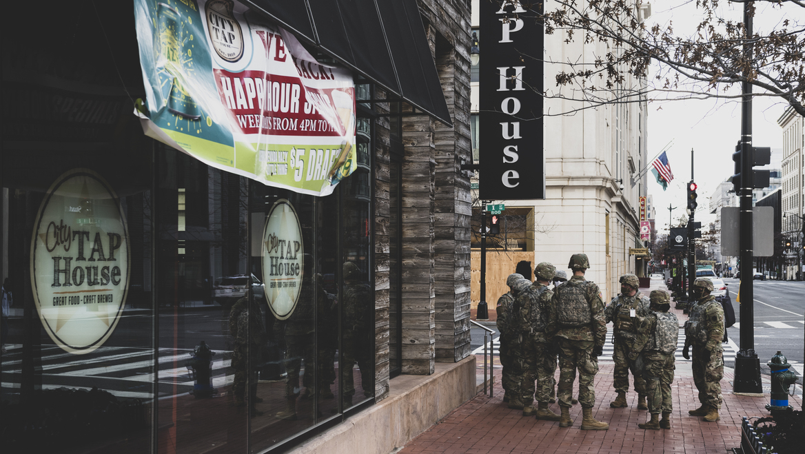 A group of federal troops stand in front of a restaurant in a city.