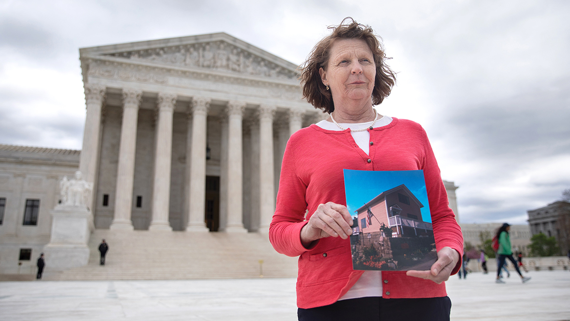 Susette Kelo, in front of the Supreme Court of the United States, holds a photo of her 'little pink house,' made famous by the 2005  Kelo v. New London court case. Photo courtesy of Institute for Justice.