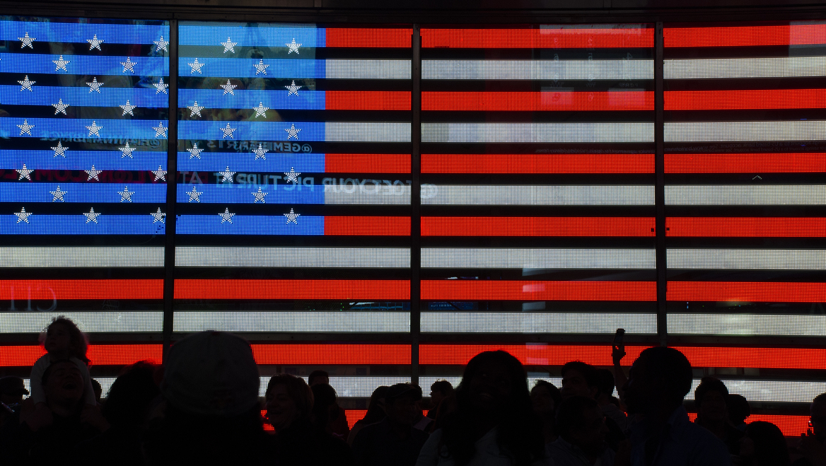 A digital screen showing the American flag with outlines of people standing in front.