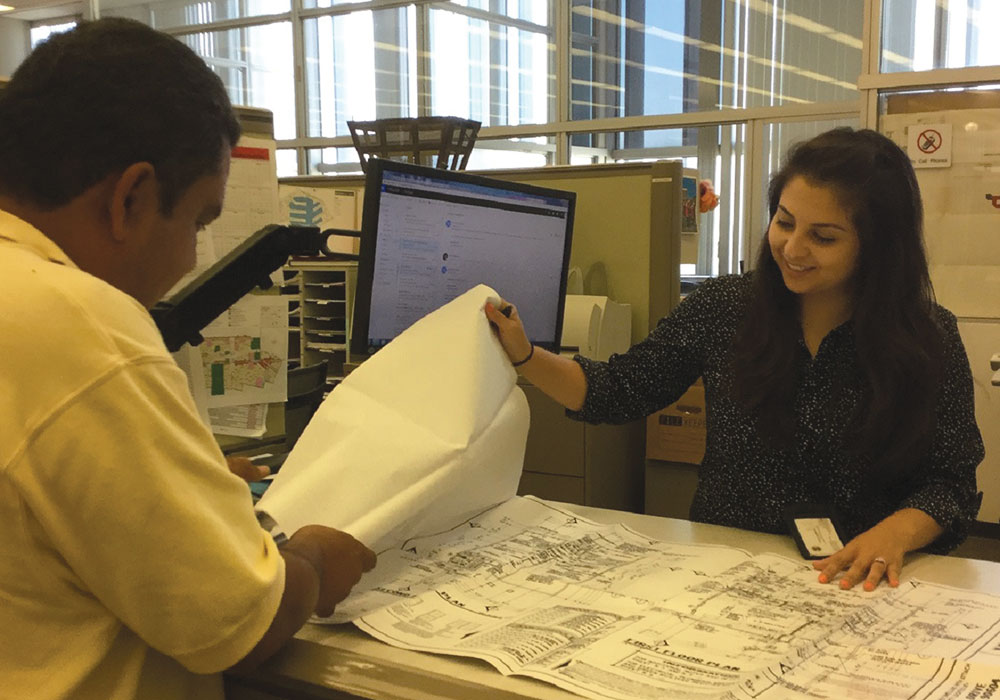 A Spanish Planning Committee member provides a property site plan to a Spanish-speaking property owner