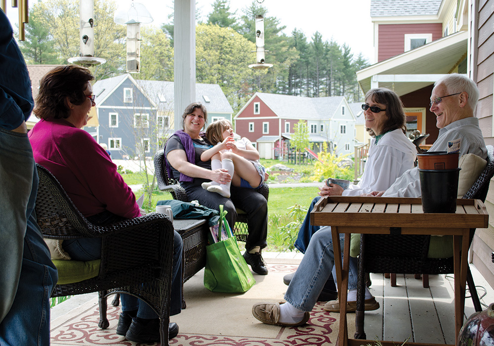 Residents chat on the porch of a home in Mosaic Commons