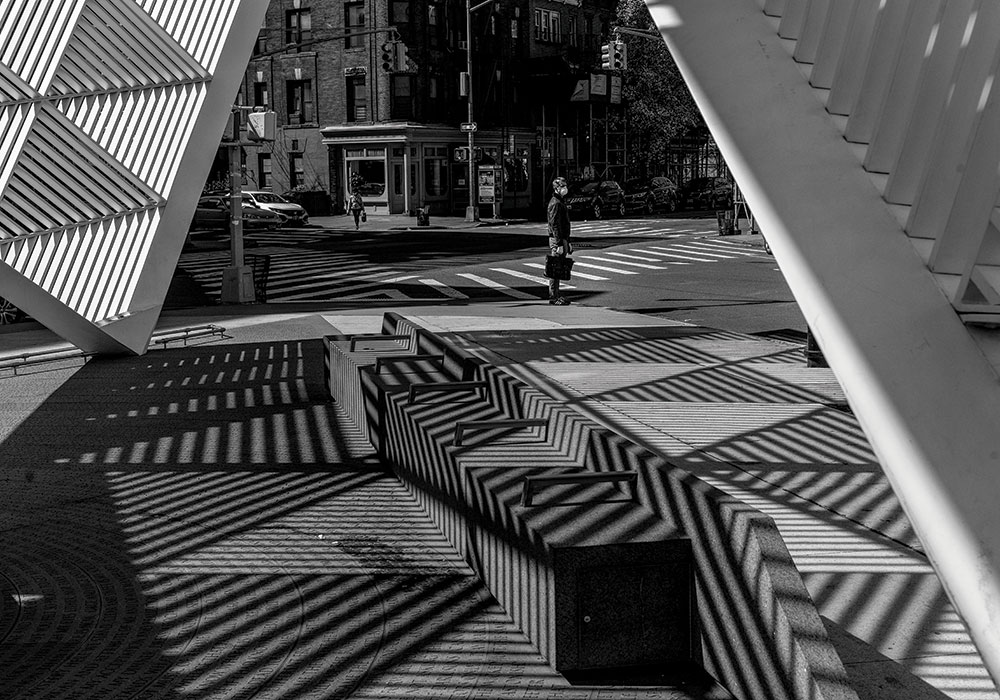 A masked pedestrian stands near the New York City AIDS Memorial, looking back toward the Lenox Health Greenwich Village hospital. Photo by Todd Heisler/The New York Times.