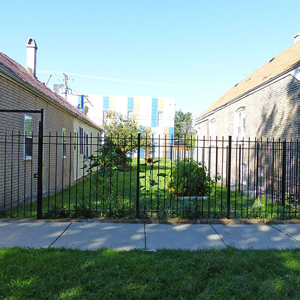 A formerly grass-covered lot has been converted to a private garden with a surrounding fence. Photos by USDA Forest Service.