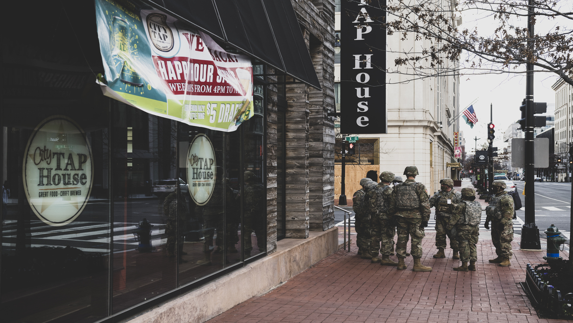 A group of federal troops stand in front of a restaurant in a city.