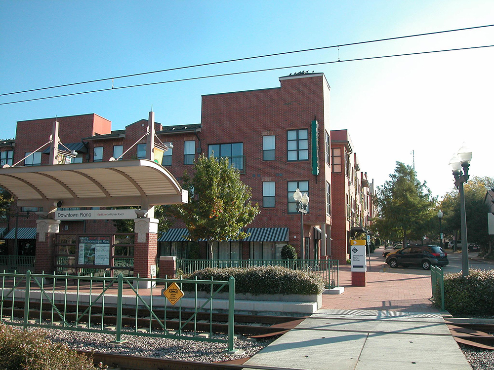 This image of transit-oriented development in Plano, Texas, includes buildings, a sidewalk, and a train station.