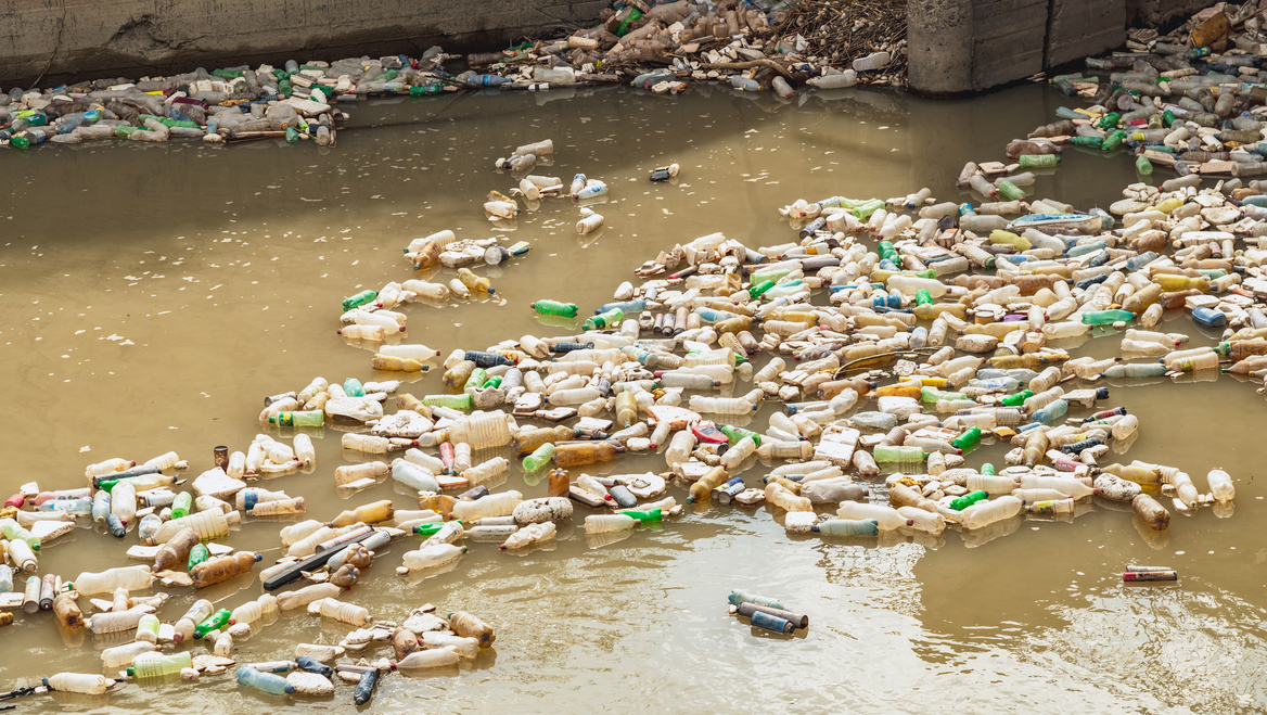 A polluted river is filled with plastic water bottles.