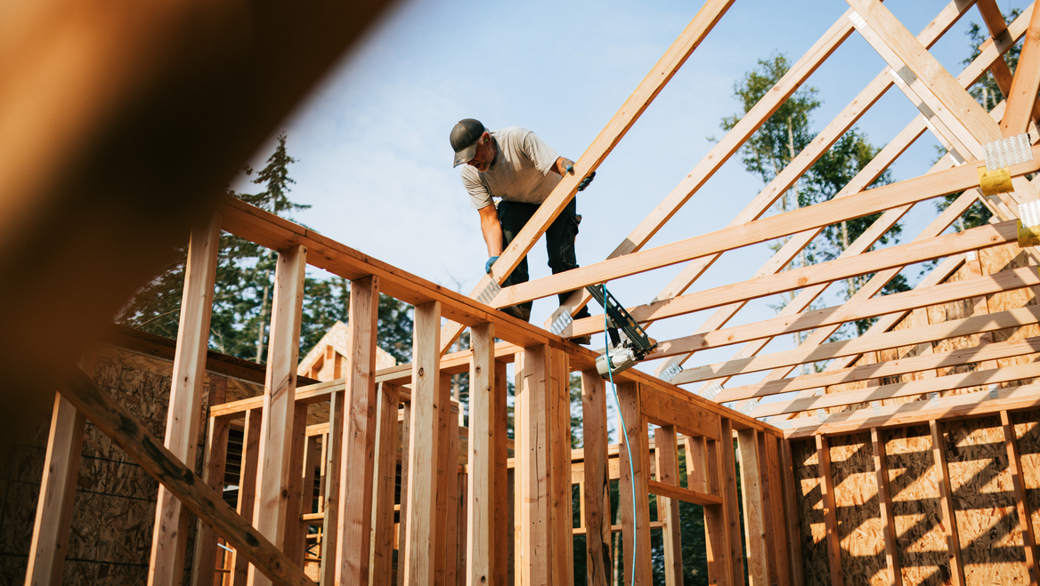 A man works to build the wood frame of a house.