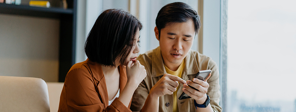 Couple looking at a smartphone screen, reviewing information together.