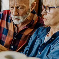older couple sitting at table looking over disaster preparedness supplies