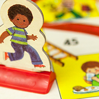 Image of vintage Chutes and Ladders board game and game piece.