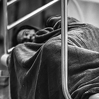Person wrapped in a blanket sleeping on a train