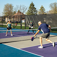 Four people playing pickleball on an outdoor court.