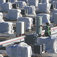 Technician inspecting solar power inverters at a sustainable energy farm.