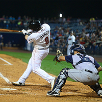 Baseball player Max Muncy hitting a pitch during a night game.