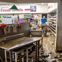 Flooded grocery store with debris and a man cleaning up.