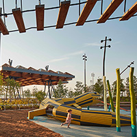 Playground with rope bridge, climbing structure, and yellow caterpillar tunnel.