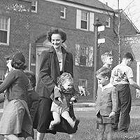 Children playing near Parkway Village sign, with adults supervising.