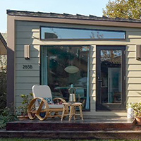 Modern tiny home with a deck and garden in a suburban backyard.