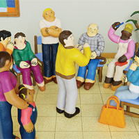 Clay figures in a support group session, with one person speaking to the group.