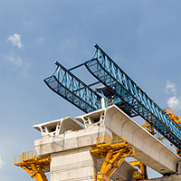 Concrete bridge construction with heavy machinery and blue sky.