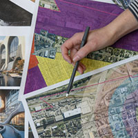 Maps laying across a table with a hand holding a pencil