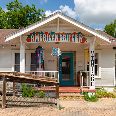 A single-story, ranch-style home that has been converted to a vintage clothing store named "American Drifter."