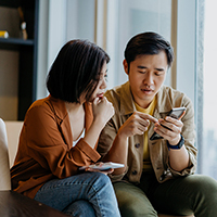 Couple looking at a smartphone screen, reviewing information together.