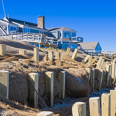 Coir logs installed at the base of a coastal sand dune with residences at the top of the dune.