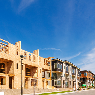 New townhouses under construction along a street with a long row of similarly scaled pedestrian-oriented new residential construction.