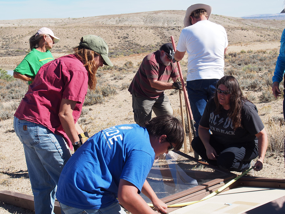 This image depicts a group of volunteers at the Great Escape Mustang Sanctuary conducting land management activities to support wild horses and public lands.