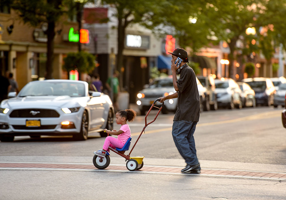 Father and daughter crossing the street in Downtown Patchogue Village. Photo by Benny Migs.