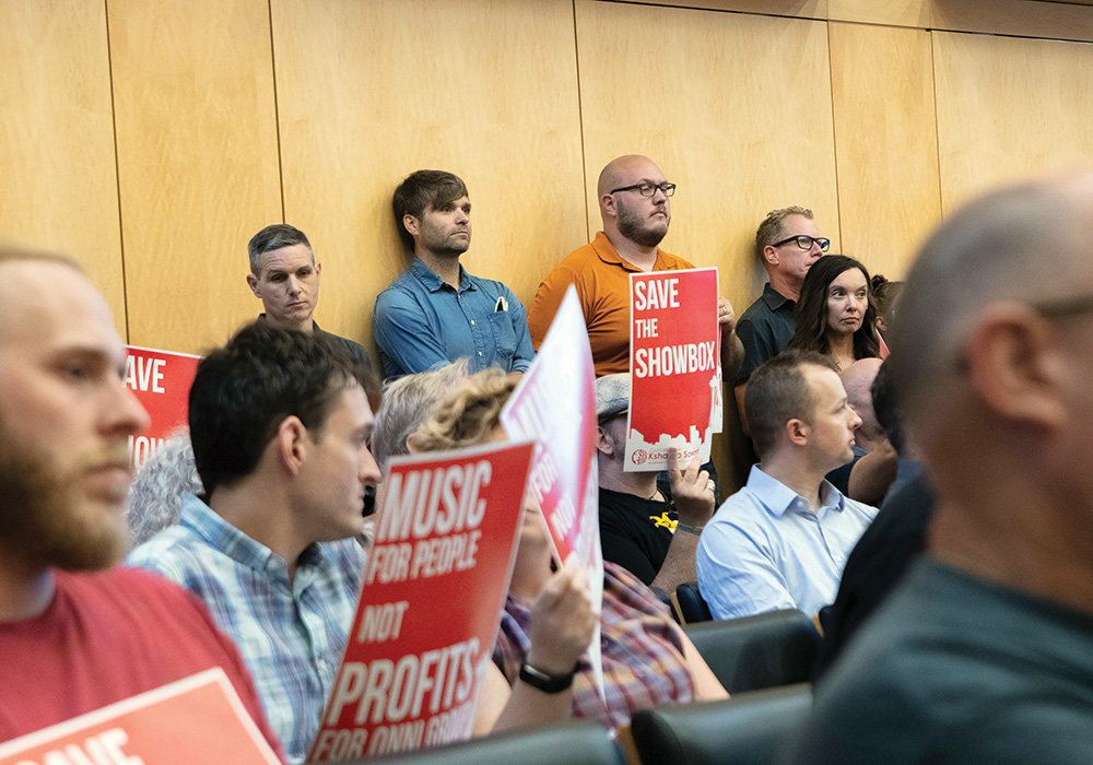 Death Cab for Cutie’s Ben Gibbard (top row, in blue shirt) waits in Seattle’s city council chambers to comment on the fate of the Showbox. Photo by Lester Black/The Stranger.