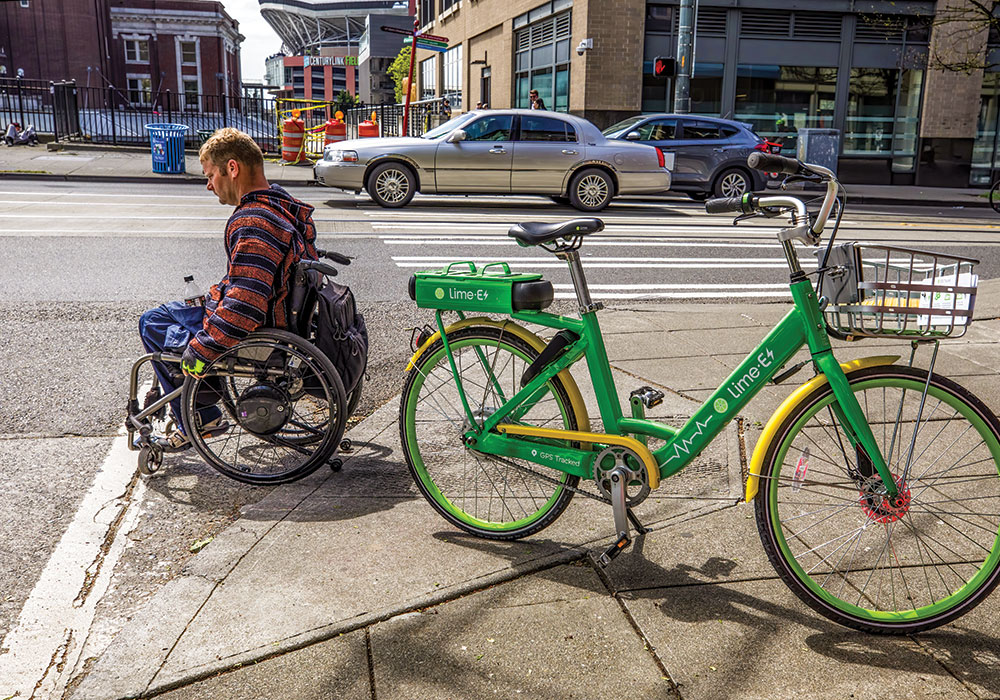 A Seattle wheelchair user maneuvers around a dockless Lime bike partially blocking a curb ramp. Photo by Steve Ringman/The Seattle Times.