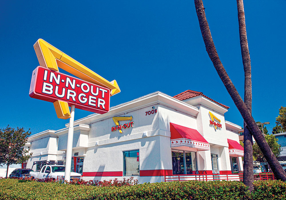 Under a bright Los Angeles sky, a big In-N-Out Burger sign and a long drive-through lane symbolize the heyday of fast food’s car-culture origins. Although some communities are fighting this typology through bans and zoning restrictions, some advocates say the drive-through model still serves a need. Photo by E. J. Baumester Jr./Alamy.