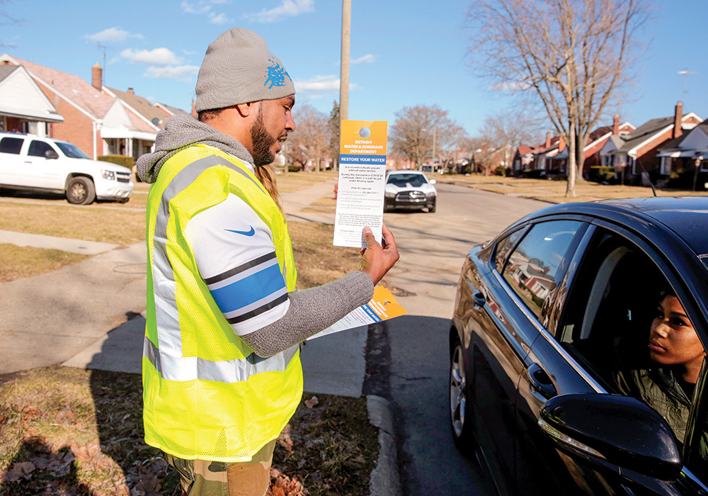 A Detroit Water & Sewerage Department employee gives information to residents about restoring their water service. The city suspended shutoffs as a public health and safety measure during the early days of the COVID-19 outbreak. Photo by Rebecca Cook/Reuters.