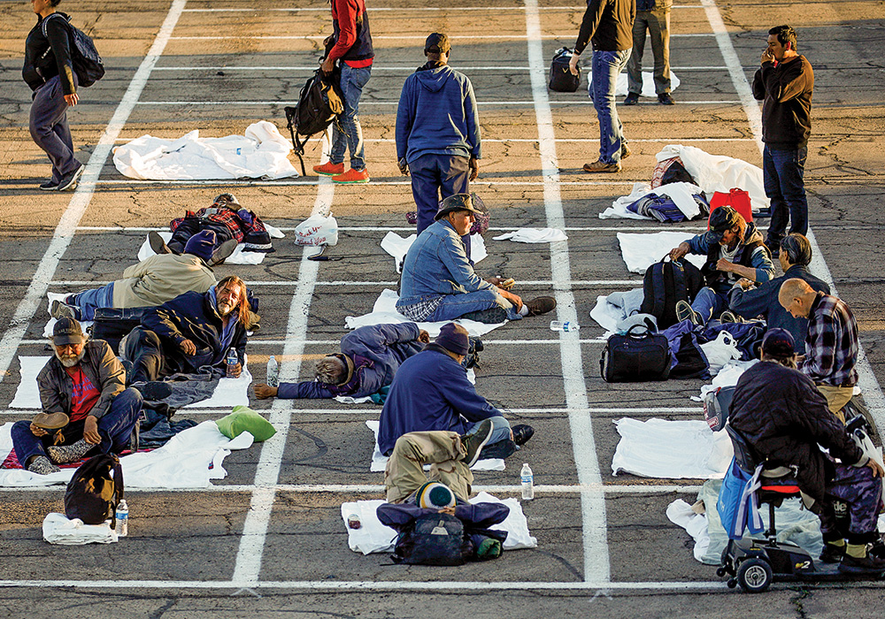 When a Las Vegas shelter temporarily closed because of a COVID-19 case, its patrons were directed to a nearby parking lot, where they spent the night six feet apart in hastily painted grids. Photo by John Locher/AP.