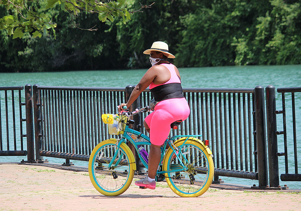 A woman bikes along the Detroit River on an air pollution alert day during the pandemic.