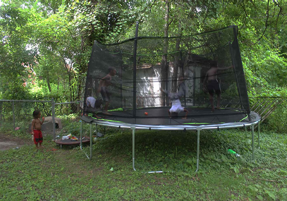 Local children play on a trampoline, which appears to be the most popular way for them to enjoy the summer of 2020 when so many of their usual activities have been canceled.