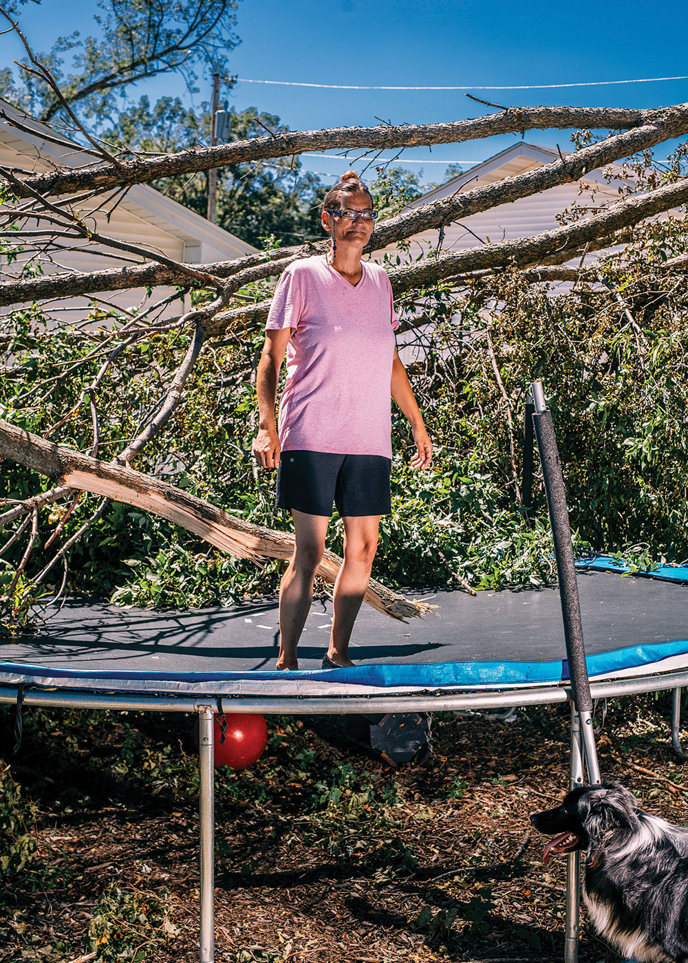 Millette Schap stands amid trees brought down in her backyard by the derecho that hit Cedar Rapids, Iowa, in August. Photo by Jordan Gale/The New York Times.