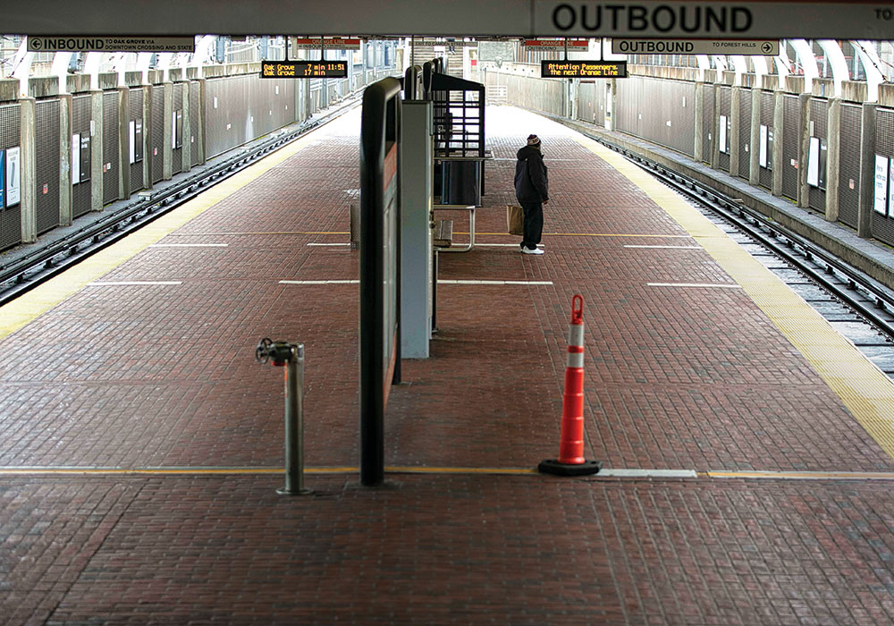 A lone traveler waits at a Boston subway station in March, when state and local governments began issuing emergency closures and mandates due to COVID-19. Photo by Katherine Taylor/The New York Times.