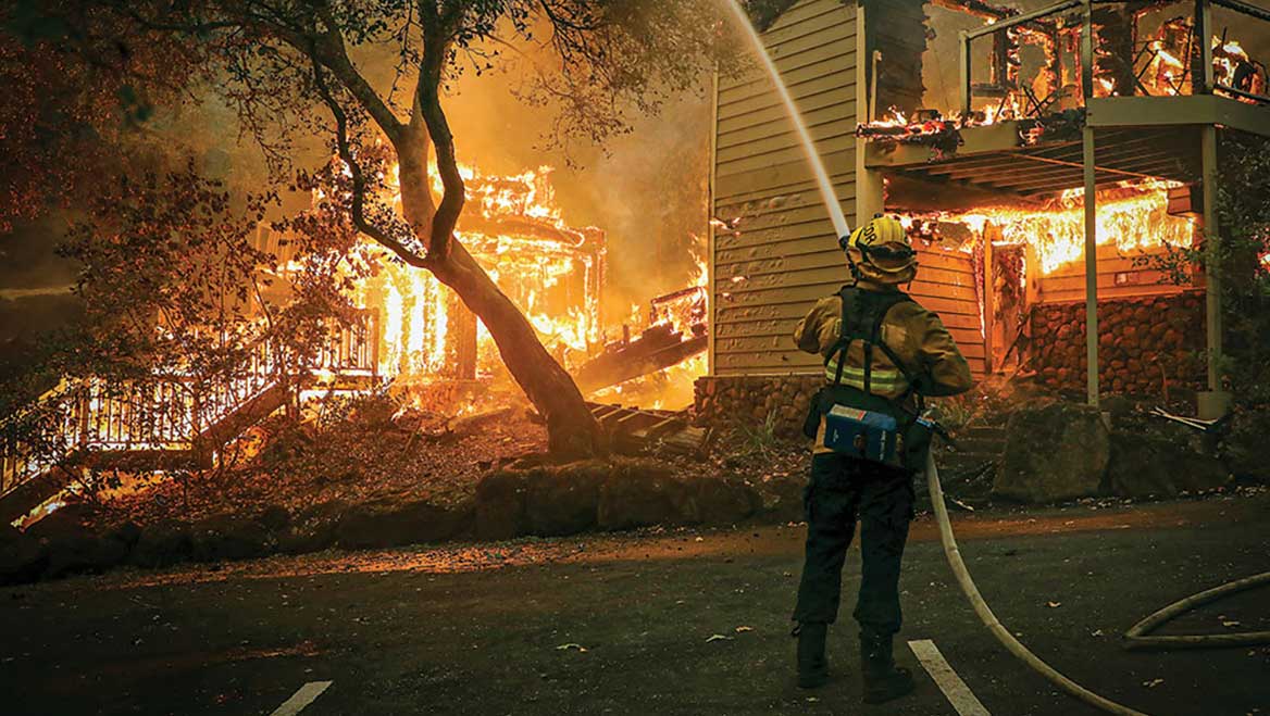 Firefighters work to put out a fire engulfing a hotel structure in St. Helena, California, in September 2020. Photo by Jim Wilson/The New York Times.